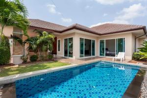 a villa with a swimming pool in front of a house at Luxury 3 bed pool villa in Ban Huai Yai