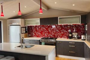 a kitchen with a red and white pattern on the wall at Mangawhai Heads Paradise in Mangawhai