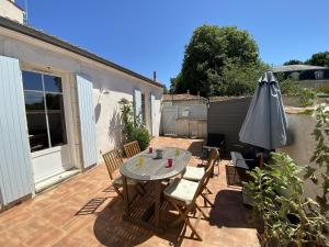 a patio with a table and an umbrella at Villa rénovée à Fouras: 2 ch + mezzanine, proche plage/centre, jardin privatif, équipement complet - FR-1-709-64 in Fouras
