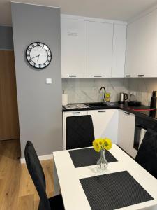 a kitchen with a table and a clock on the wall at Apartament Grey 2 pokojowy z balkonem w Warszawie z parkingiem podziemnym in Warsaw