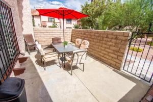 a patio with a table and a red umbrella at Spacious 2-Bedroom Townhouse with Pool & Private Patio in Central Las Vegas in Las Vegas