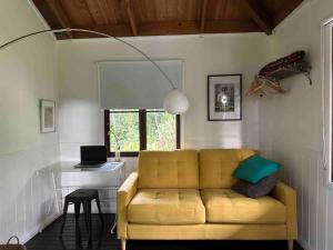 a living room with a yellow couch and a desk at Cow Bay Cabin in Cow Bay