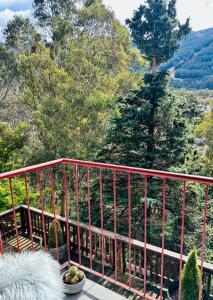 a red metal railing on a balcony with trees at First Tracks Studio in Thredbo
