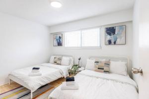 two beds in a room with white walls at Beautiful Vancouver Special Home in Vancouver