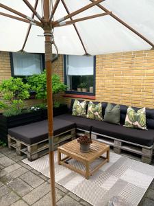 a patio with a black couch and an umbrella at Lovely villa at the foot of the Funen Alps in Fåborg +40 photos
