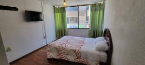 a bedroom with a bed and a window with green curtains at Hostal María - Otavalo in Otavalo