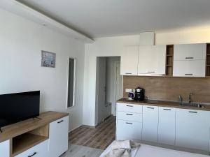 a kitchen with white cabinets and a flat screen tv at Студио Симона 5 първа линия море in Lozenets