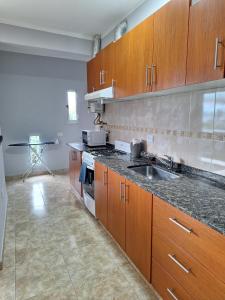 a large kitchen with wooden cabinets and a sink at Departamentos Güemes in San Fernando del Valle de Catamarca