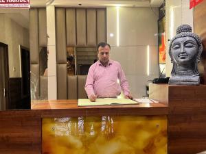 a man sitting at a desk with a statue at Hotel Haridev in Roorkee