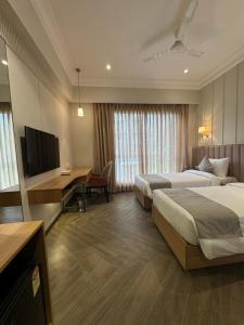 a hotel room with two beds and a desk and a television at Hotel Mumbai House Mindspace Malad in Mumbai +16 photos