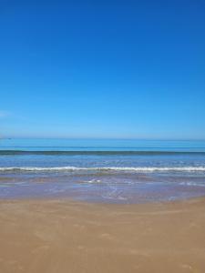 a sandy beach with the ocean in the background at Residence les jardins cap de l eau in Ras El Ma