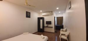 a white room with a bed and two chairs at COSY CHAMBRE in Puducherry