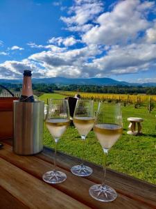 three wine glasses sitting on a table with a bottle of wine at The Small House - Mid century gem in wine county's Healesville in Healesville