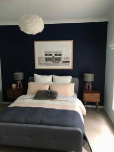 a bedroom with a large bed with a blue wall at The Small House - Mid century gem in wine county's Healesville in Healesville