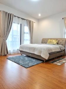 een bed in een slaapkamer met een houten vloer bij PS home โฮมฮักขอนแก่น in Ban Non Sa-at
