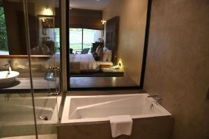 a bathroom with a bath tub and a bedroom at Sigiriya King's Resort in Sigiriya