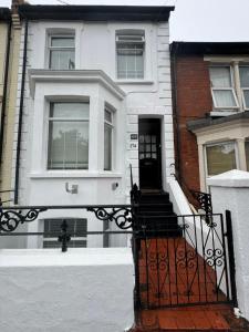 a white house with a black gate in front of it at Shine Lodge in Kent