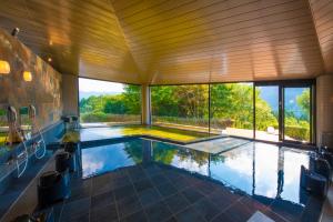 a swimming pool in a house with a large window at The ACONCAGUA RESORTS in Minami Aso