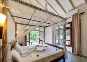 a bedroom with a canopy bed with a window at White Villa Goyambokka - Private Pool Villa in Tangalle