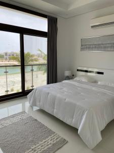 a white bedroom with a large bed with a view of the beach at Stella Salalah in Salalah