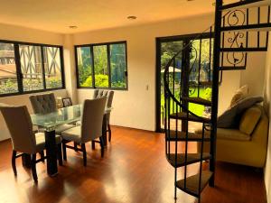 a dining room with a glass table and chairs at Alojamiento tipo Cabaña, rodeado de Bosque in Mexico City