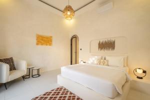 ein weißes Schlafzimmer mit einem Bett und einem Stuhl in der Unterkunft Villa Affinity Canggu by OriVista Great Location in Canggu