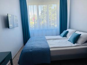 a bedroom with a bed with blue curtains and a window at NB Apartamentai in Palanga