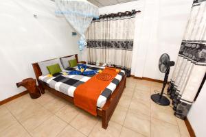 a bedroom with a bed and a fan in it at Elephant Trio Sigiriya in Sigiriya
