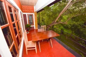 a porch with a wooden table and chairs on a balcony at Elephant Trio Sigiriya in Sigiriya