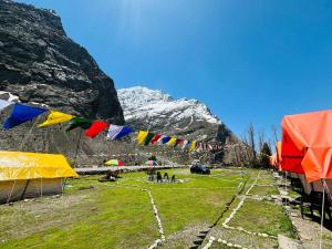 a group of tents and flags in a field with a mountain at Kinzom Valley Camps in Jispa