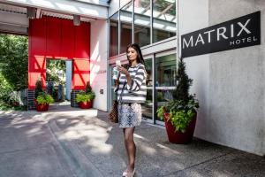 a woman standing in front of a store talking on a cell phone at Matrix Hotel in Edmonton