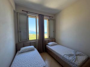 two beds in a room with a large window at Onis Sea View Apartments in Orikum