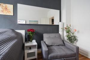 a bedroom with a bed and a chair and a mirror at Schicke Altbauwohnung in Kiel Mitte 24-7 Check In in Kiel