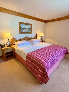 a bedroom with a large bed with a plaid blanket at Crystal Hotel superior in St. Moritz