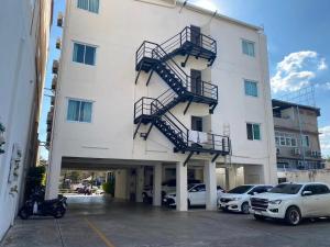 a large white building with stairs in a parking lot at Tisa Hotel Udonthani in Udon Thani