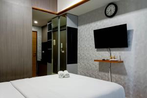 a bedroom with a bed with a tv on the wall at Relaxing Studio at Vida View Makassar Apartment By Travelio in Pampang