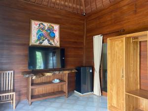 a living room with wooden walls and a flat screen tv at Lembah Cinta Mayungan in Baturiti