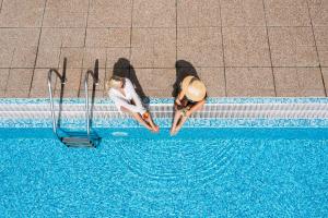 two women are standing next to a swimming pool at Four Points by Sheraton Sunny Beach in Sunny Beach