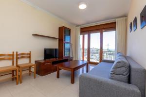 a living room with a couch and a table and a television at Apartamentos Eira Do Mar Sanxenxo in Aios