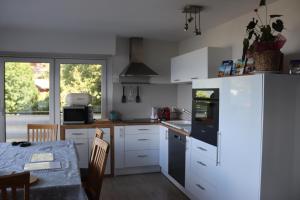 a kitchen with white cabinets and a table and a dining room at Comme sur un nuage, appartement pour 4 personnes in Nendaz