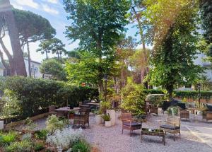 a garden with chairs and tables and trees at Hotel B&B Des Bains Milano Marittima in Milano Marittima