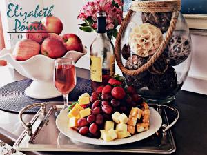 a tray with a plate of fruit and a bottle of wine at Elizabeth Pointe Lodge in Fernandina Beach