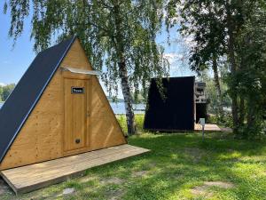 a small tent sitting in the grass next to a tree at Triangeli -glampingmökki in Hämeenlinna