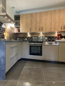 a kitchen with stainless steel appliances and wooden cabinets at Maison de charme Vallée de la Rance DINAN LANVALLAY in Lanvallay