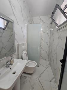 a white bathroom with a sink and a toilet at Hotel Irini in Sarandë +83 photos