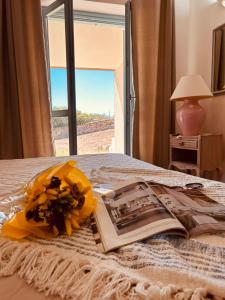 a book and flowers on a bed with a window at Villa Violetta Relais in Marina di Portisco