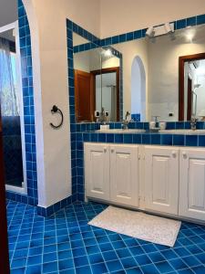 a bathroom with two sinks and a blue tile floor at Villa Violetta Relais in Marina di Portisco