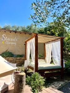 a wooden swing in a garden with white curtains at Stecadó Glamping in Dolceacqua