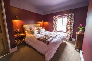une chambre avec un lit aux murs violets et une fenêtre dans l'établissement Large Country Cottage, Sleeps 8 - Spa Facilities, Garden Bar, Catering Services, Free Parking, Nature Reserve, Hen Parties, à Scunthorpe