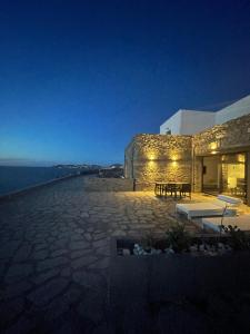 a stone building with a bench next to the ocean at Ocean Villa Paros in Sarakíniko